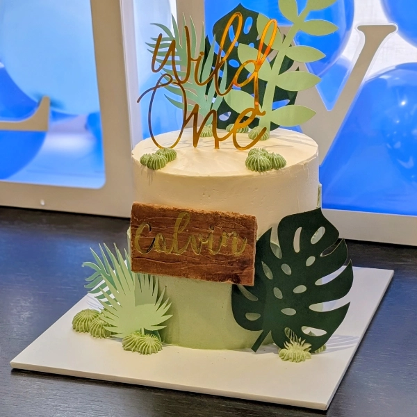 A green and white jungle themed birthday cake for a one year old